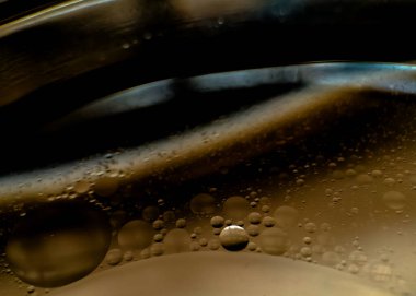 Soyut arkaplan, yağ damlacıkları suda asılı duruyor, farklı boyutlarda daireler çiziyor..