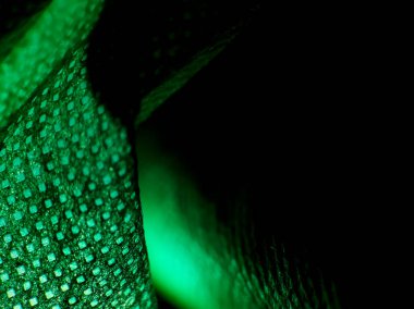 Parlak yeşil bir kumaş yüzeyine yakın çekim, karmaşık doku ve desen gösteriyor. 