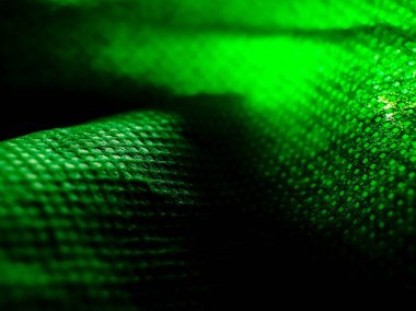 Parlak yeşil bir kumaş yüzeyine yakın çekim, karmaşık doku ve desen gösteriyor. 