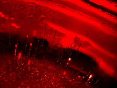 Condensation and droplets cover the inside surface of a container, with a blue ice cube visible at the bottom.