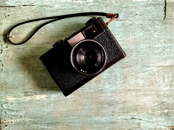 old photo camera placed on a distressed turquoise wooden surface, creating a rustic backdrop