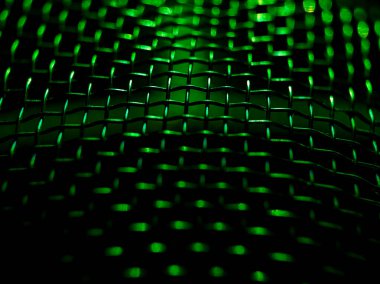 Birbirine dolanmış metal kabloların yakın çekimi yeşil ışıkla aydınlatılan bir ağ oluşturuyor.. 