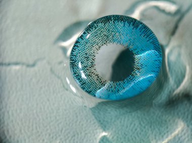 Benekli desenli mavi kontakt lens görünür su damlacıklarıyla açık mavi dokulu bir yüzeye dayanır.. 