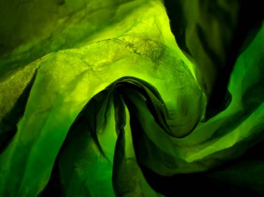 Buruşmuş kağıt dokusu parlak yeşil ışıkla aydınlatılır ve soyut bir arkaplan oluşturur.. 