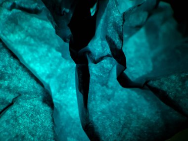 Buruşmuş kağıt dokusu parlak mavi bir ışıkla aydınlanır ve soyut bir arkaplan oluşturur.. 