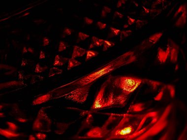 Kırmızı ışık, üçgen şekilli desenli cam bir yüzeyi aydınlatır ve soyut ve karmaşık bir tasarım yaratır.. 