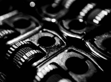 Soyut siyah beyaz arkaplan. Arka arkaya dizilmiş bir grup metal sigara çakmağı tekerleğinin yakın çekimi. 