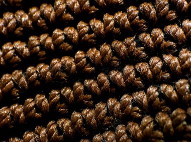 Kahverengi iplikten yapılmış desenli bir çanta yüzeyi..