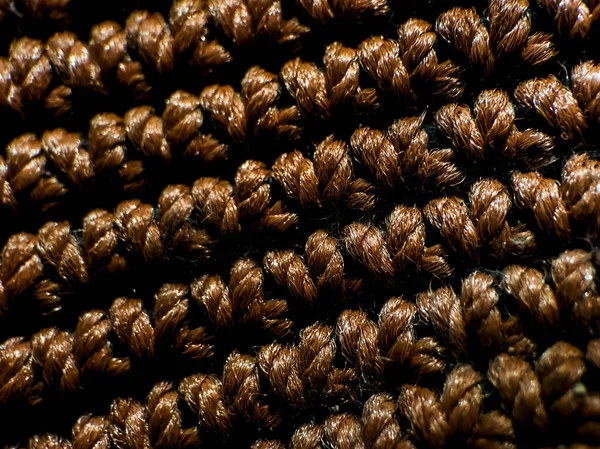 Kahverengi iplikten yapılmış desenli bir çanta yüzeyi..