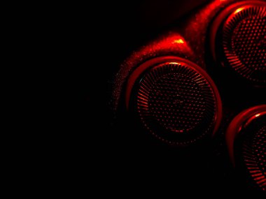 Dairesel, desenli metal yüzeyler koyu arkaplana karşı kırmızı ışıkla aydınlatılır.. 