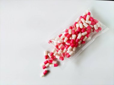 Beyaz bir yüzeyde saydam bir plastik torba sayısız kapsül içerir.. 