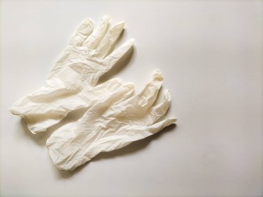 Lateksten yapılmış iki beyaz tek kullanımlık tıbbi eldiven düz bir yüzeye serilmiştir..