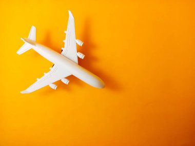 Saf turuncu arka planda beyaz oyuncak uçak.