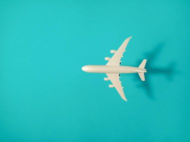 Küçük beyaz bir uçak oyuncağı mavi bir arka planda merkezlenir..