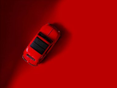 Kırmızı bir oyuncak araba canlı kırmızı bir yüzeye yerleştirilir ve tek renkli bir etki yaratır..