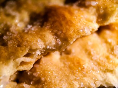 Bisküvinin yüzeyine yakın çekim, altın kahverengisini, çıtır çıtır dokusunu gösteriyor. Şekerin kristalleri tüm yüzeye dağılmış, parlak bir etki yaratıyor..