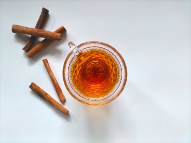 Beyaz bir yüzeyde sıcak tarçınlı cam bardak..