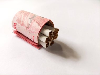 Birkaç sigara, 100.000 Endonezya Rupia banknotuyla birlikte paketlenerek silindirik bir şekil alır..