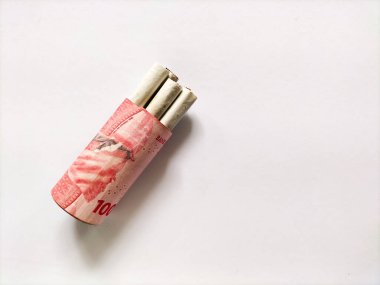 Birkaç sigara, 100.000 Endonezya Rupia banknotuyla birlikte paketlenerek silindirik bir şekil alır..