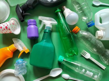 Plastik atık yeşil bir yüzeye saçıldı. Çevresel ya da geri dönüşüm teması önermek.