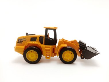 Plastik olarak dizayn edilmiş önyükleyicili sarı oyuncak traktörü, düz beyaz bir arka planda yer almaktadır..