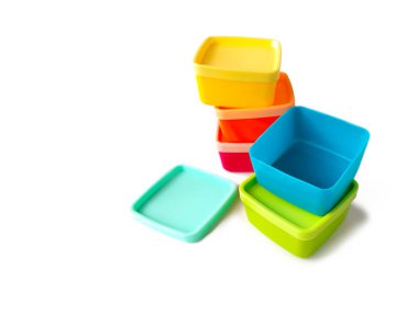 Kare plastik gıda kapları canlı renklerde beyaz arka planda bir araya toplanmış..