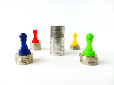 Renkli plastik satranç piyonları para yığınlarının üzerine yerleştirilmiş merkezdeki daha uzun bozuk paraların etrafını sarmışlar..