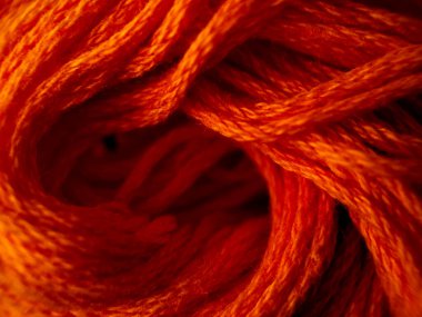 Kalın turuncu iplikler sıkıca birbirine dolanmış, canlı ve dokulu bir desen oluşturuyor..