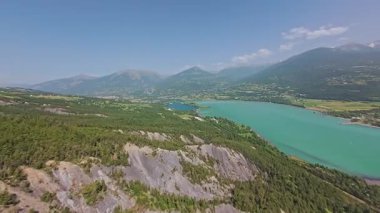 Haziran 2025 başlarında, Fransa, Serre-Ponon Gölü. Dağlardan geçen yol otobanın dışında. Turkuaz gölün dağ zirveleri.