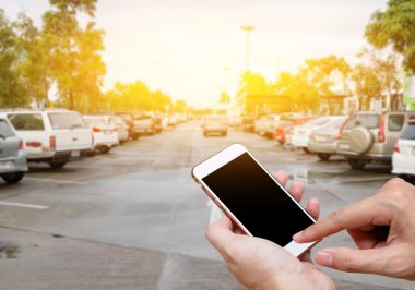Akıllı telefon ile adam elinde boş ekran gösterilen bulanıklık otopark arabalar