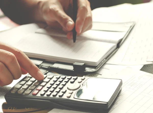 Ahorro, finanzas, economía y concepto de hogar - primer plano del hombre con calculadora contando anotaciones en casa, mano se escribe en un cuaderno con libros, enfoque suave . — Foto de Stock