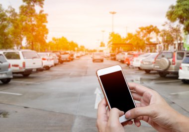 Akıllı telefon ile adam elinde boş ekran gösterilen bulanıklık otopark arabalar