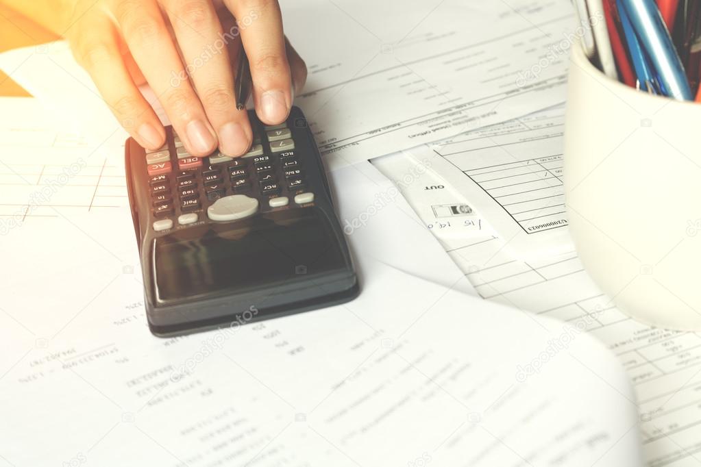 savings, finances, economy and office concept. Business people counting on calculator sitting at the table. Close up of hands and stationery, soft focus