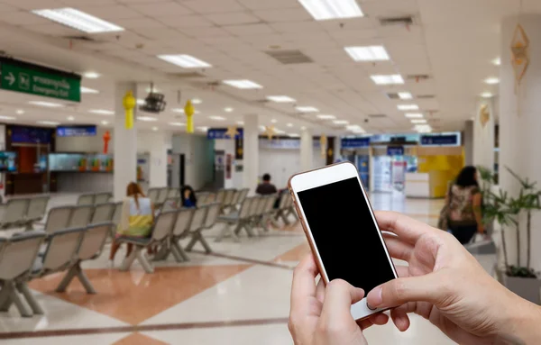 Humano celebración de pantalla en blanco de teléfono inteligente y espera llegadas ttime fondo borroso . — Foto de Stock