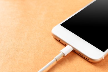 Akıllı telefon ahşap tahta üzerinde güç bankası ile şarj, yumuşak odak.