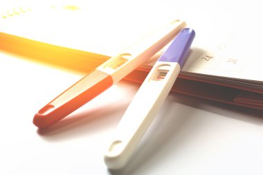 Takvim arka planında pozitif sonuç içeren gebelik testi