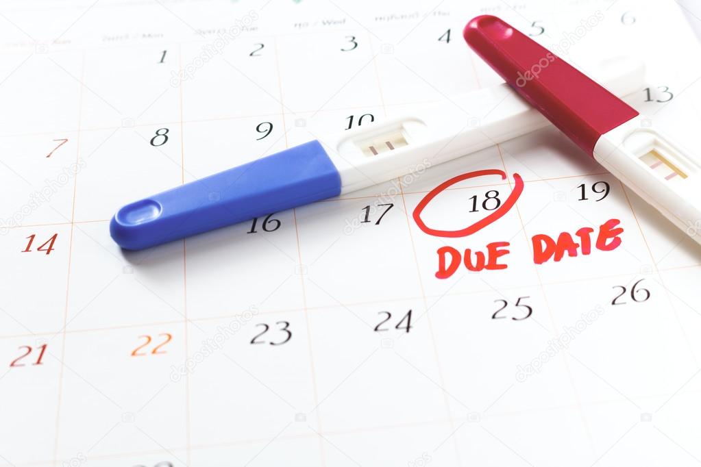 Pregnancy test with positive result lying on calendar background
