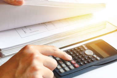 Finansal veri analizi. tasarruf, finans, ekonomi. Ofiste ya da evde hesap makinesi ne sayan bir işadamının elinin yakın çekim fotoğrafı. Yumuşak odaklama