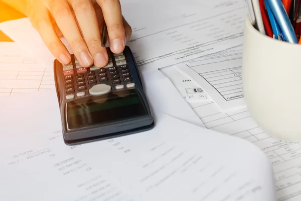 Ahorro, finanzas, economía y concepto de oficina. La gente de negocios cuenta con calculadora sentada a la mesa. Cierre de manos y papelería, enfoque suave — Foto de Stock