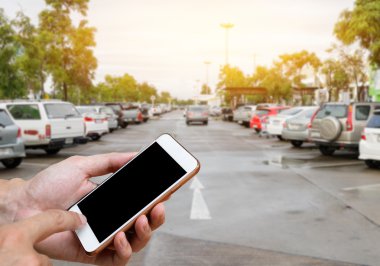 Akıllı telefon ile adam elinde boş ekran gösterilen bulanıklık araba park
