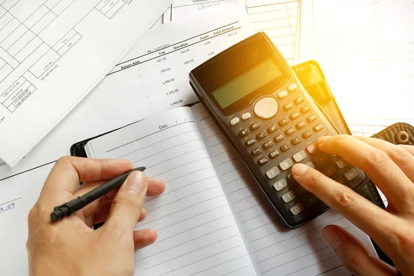 Savings, finances, economy and home concept - close up of man with calculator counting making notes at home, hand is writes in a notebook with books, soft focus. — Stock Photo, Image