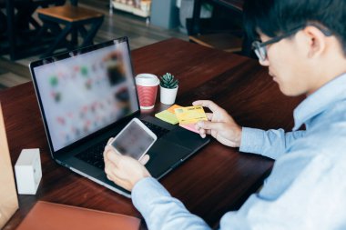 Adamın elleri akıllı telefonlar tutuyor ve kredi kartı numaralarını tutuyor. Ürün almak için internet sitelerine giriyorlar..