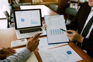 Ofis odasındaki bütçe toplantısında finansal planlama grafiği ve şirket bütçesini tartışan iki iş ortağı analiz stratejisi.