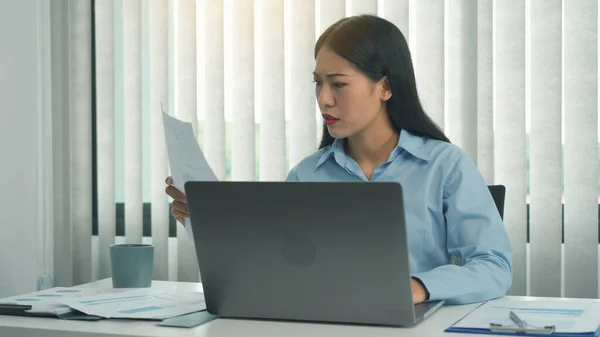 若いアジアの女性はオフィスでノートパソコンを使用している間 文書について不満を持っています — ストック写真