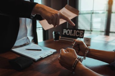 Polis memuru, bir dolandırıcılık davasında sanığı tutuklamak için kelepçeleri ve belgeleri gösterdi..