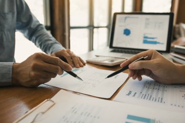 Ofis odasındaki bütçe toplantısında finansal planlama grafiği ve şirket bütçesini tartışan iki iş ortağı analiz stratejisi.