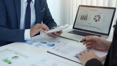 Bir grup işadamı, işletme işletme giderleri ve şirketin mali durumuyla ilgili çalışma verilerinin özet grafik raporlarını analiz ediyor..