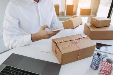 Asyalı genç adam evdeki siparişleri kontrol etmek için akıllı telefon kullanıyor..