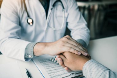 Doktor hastanın elini tutuyor ve hastalığın semptomlarını tedavi etmek için umut veriyor..