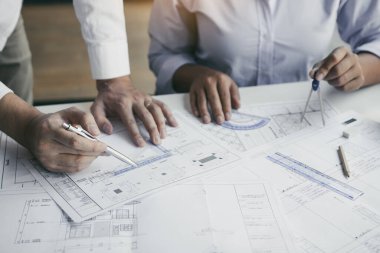 Ortaklık mühendisi ya da iş arkadaşı bir proje üzerinde çalışıyor ve plan belgelerine bakmakla birlikte tartışıyorlar..